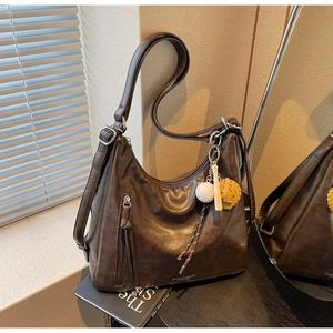 Close-up of dark brown hobo tote bag featuring a leather tassel and baseball-themed charm