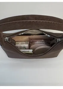 Internal view of dark brown suede shoulder bag showing storage space for cosmetics
