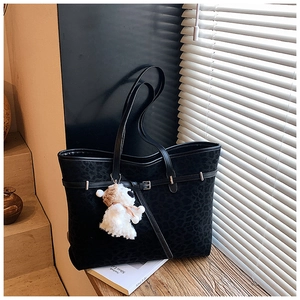 Detail of vintage black leopard tote bag with puppy charm and leather strap buckle decoration