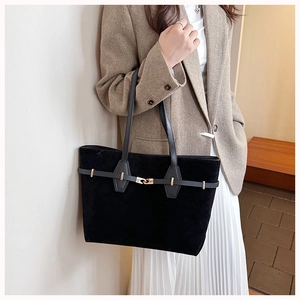 Detailed view of black suede tote bag featuring a decorative gold buckle and sleek texture