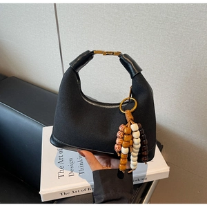 Détail du sac en tissu noir avec base en cuir et accessoire en perles de bois colorées