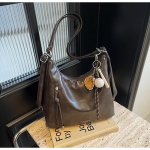 Detail of vintage brown leather tote bag with baseball pendant and fringe zipper pocket