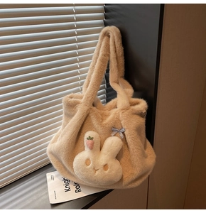 Detail shot of a plush beige tote bag featuring a cute rabbit and bow charm