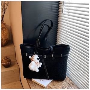 Detail of black leopard print tote bag with buckle strap and plush bear charm