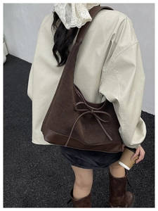 Detail of vintage brown tote bag featuring suede leather and side bow decoration