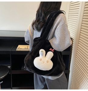 Detail of a large black fuzzy tote bag featuring a cute white plush bunny and red bow