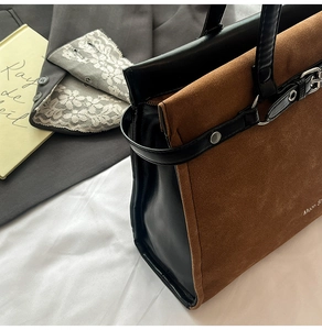 Detail of vintage tote bag featuring brown suede stitching and black leather strap accents