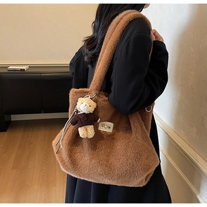 Gedetailleerd beeld van bruine pluche draagtas met logopatch en teddybeer hanger accessoire