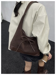 Detailed street style view of deep brown suede tote bag with bow detail and large capacity