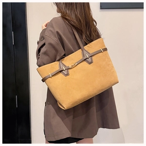Detail view of a large camel suede tote bag worn on shoulder for commuting