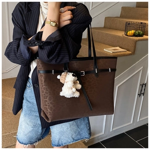 Close-up of leopard pattern vintage tote bag with leather straps and plush charm