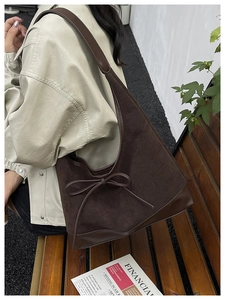 Detail of a large vintage brown suede tote bag with a decorative leather bow accent
