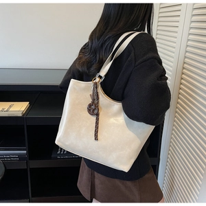 Detail einer großen cremefarbenen Shopper mit gewebtem Anhänger am Schulterriemen