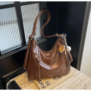 Close-up of brown PU leather tote with tassel zipper and baseball charm detail