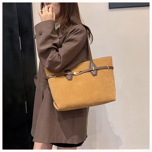 Detail of a large yellow tote bag with dark brown leather strap and gold metal buckle