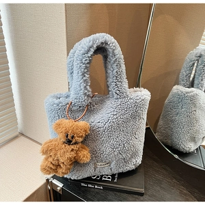 Close-up of blue fuzzy fleece handbag with bear charm and CLEAROK patch detail