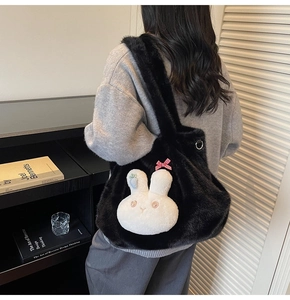 Model wearing a black plush tote bag featuring a cute bunny head and blue carrot embroidery