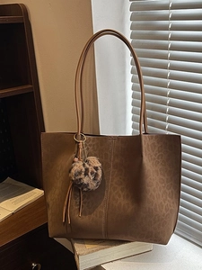 Brown leopard print large tote bag with plush heart charm on white windowsill