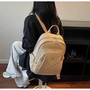 Close-up of beige lychee grain leather backpack with multiple zipper compartments