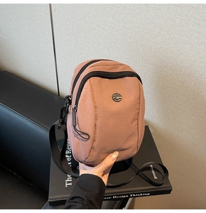 Detail of dusty pink canvas crossbody bag showing dual zipper pockets and adjustable strap