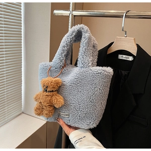 Detail of light blue fuzzy bucket bag featuring a clear label and cute bear charm
