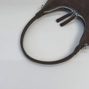 Detail of vintage brown leather handbag featuring silver double zippers and texture