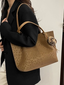 Large leopard print tote bag in brown synthetic leather with faux fur charm on a model