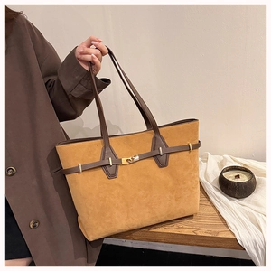Detail of a vintage ginger yellow suede tote bag with brown straps and gold hardware
