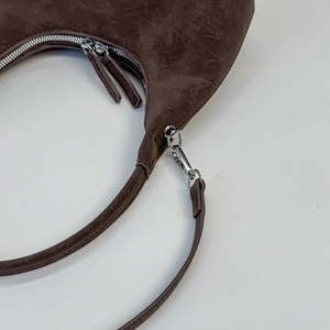 Detailed macro view of dark brown oil-wax leather texture and silver zipper hardware
