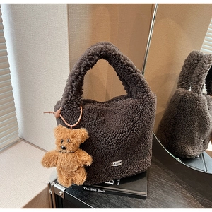 Close-up of brown plush bucket bag with curly faux fur texture and teddy bear charm