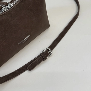 Detail of vintage dark brown faux leather bag with silver logo and adjustable strap