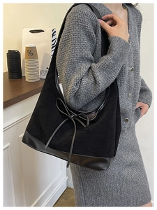 Close-up of black suede tote bag with leather bow detail and smooth leather base
