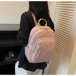 Detailed close-up of light pink lychee texture PU leather backpack with silver zippers