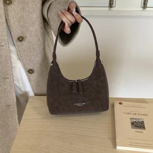 Detail view of dark brown crescent bag with white fashion text and double zippers