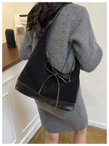 Detail of vintage black suede tote bag with leather piping and decorative bow accent