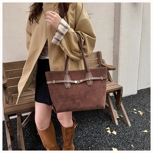 Detail of dark brown suede tote bag with decorative straps during autumn outdoor street style