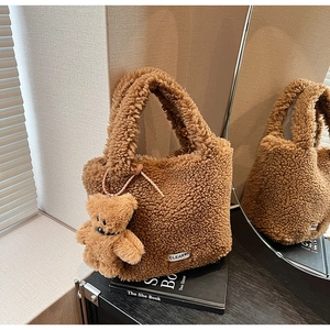 Detail of soft brown faux fur bucket bag featuring a cute teddy bear charm and logo tag