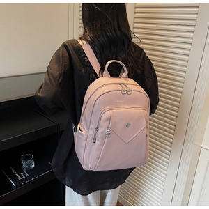 Detail view of pink lychee grain leather backpack with metallic logo and circular zipper