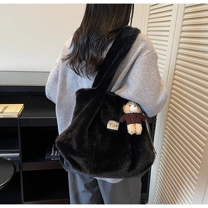 Detailopname van de zwarte hobo-tas van imitatiebont met een schattige teddybeertje