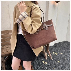 Detail of deep brown suede tote bag featuring slim leather straps and metal buckle closure