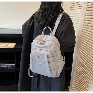 Detailed back view of a light gray lychee leather backpack worn by a model