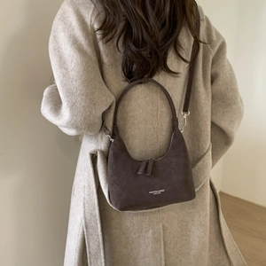 Detailed view of coffee brown suede hobo bag worn with a beige autumn cashmere coat