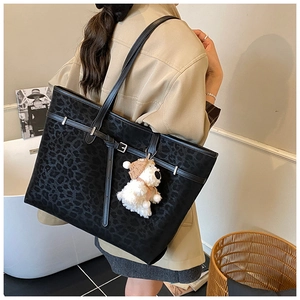 Detail of black animal-textured tote bag with plush charm and stylish slim shoulder straps