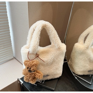 Close-up of white plush bucket bag with BEAR label and brown teddy bear charm detail