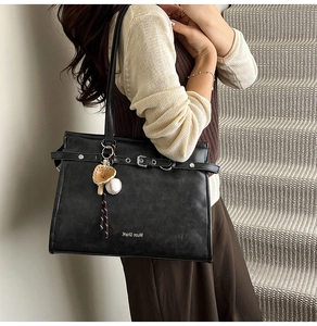 Detail of black matte leather tote bag with silver rivets and baseball glove charm