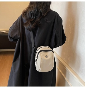 Back view of model wearing a beige canvas crossbody bag with adjustable black strap