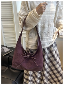 Retro deep purple suede tote bag with leather bow detail shown on shoulder with winter outfit
