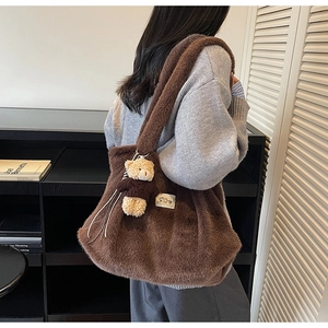 Detailopname van bruine pluche shopper met een schattige berenhanger en merklabel erop