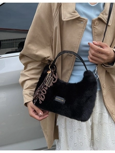 Modische schwarze Kunstpelz-Handtasche mit Schultergurt, getragen von einem Modell