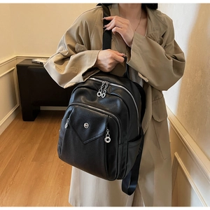 Modern black lychee texture leather backpack shown on a model in a stylish indoor setting